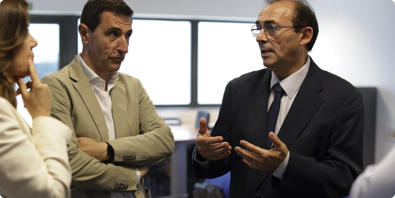 Tres profesionales conversando en una sala de reuniones
